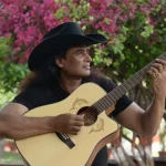 Indian country singer Bobby Cash with his guitar wearing a cowboy hat